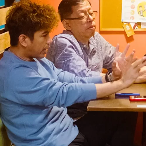 Francis and his teammate are seated at a table in a casual setting, engaged in conversation